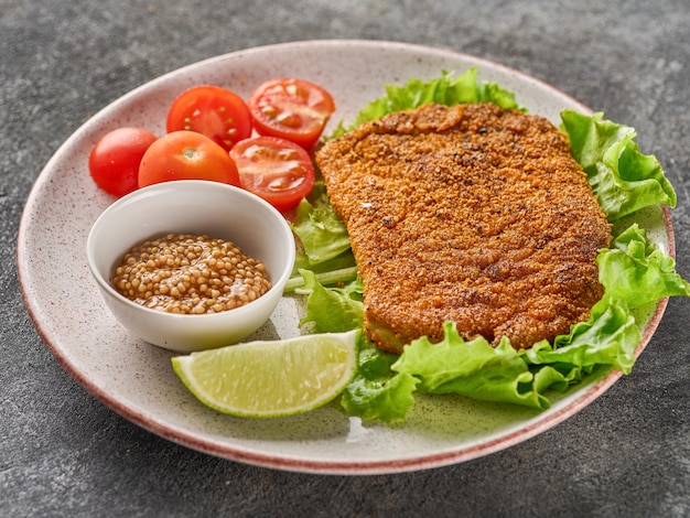 Breaded pork cutlet with cherry tomatoes mustard and lemon