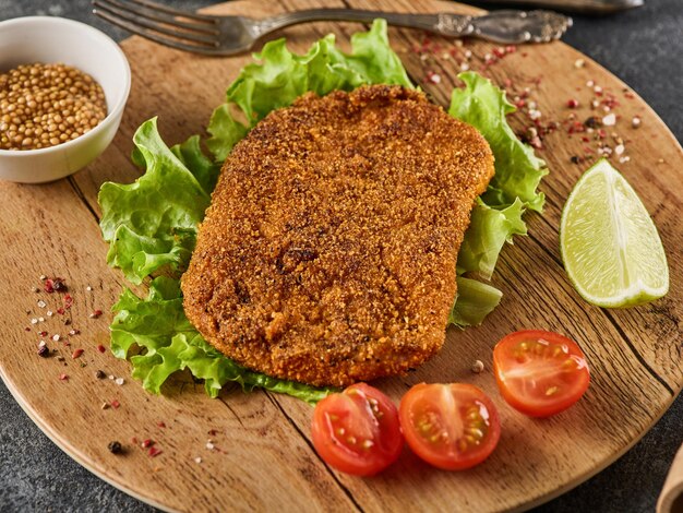 Breaded pork cutlet with cherry tomatoes mustard and lemon