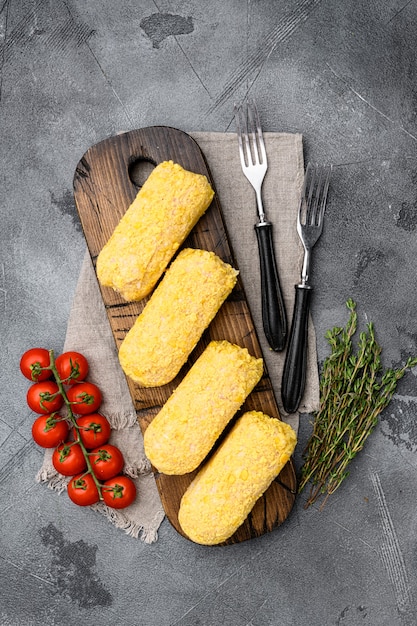 Breaded ready to cook fresh raw chicken Kiev set, on gray stone table background, top view flat lay