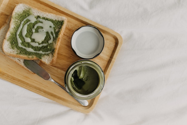 Photo breads and green tea matcha jam on wooden plate.