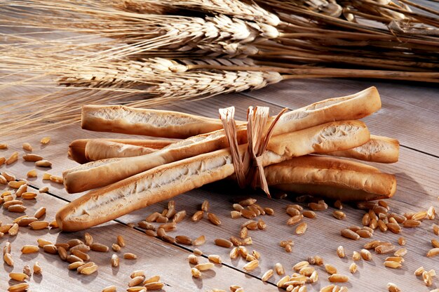 Breadsticks with ears of corn on a wodden table