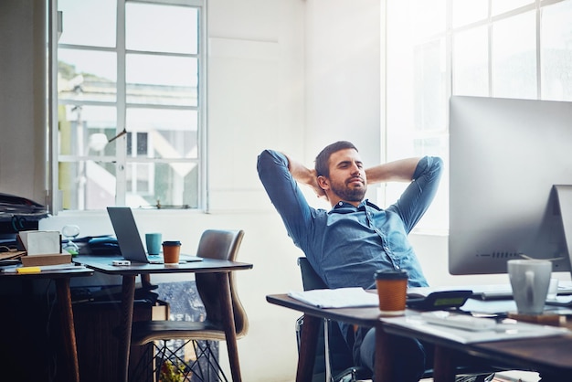 break relax and business man at office desk for stretching productivity or done with project smile computer and employee with arms behind head for satisfied achievement or deadline complete