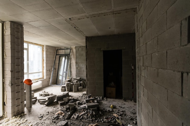 Rompere il muro per lavori di ristrutturazione e costruire la porta d'ingresso dell'edificio. carriola con mattoni rotti nella costruzione del sito.