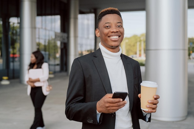 Break at work company smiling man dressed in blazer stands in front of glasswalled business