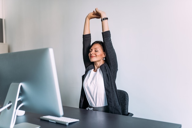 Photo break at work. female office worker stretching hands.