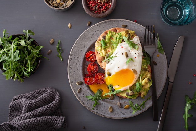 Breakfast avocado sandwich with fried egg and tomato