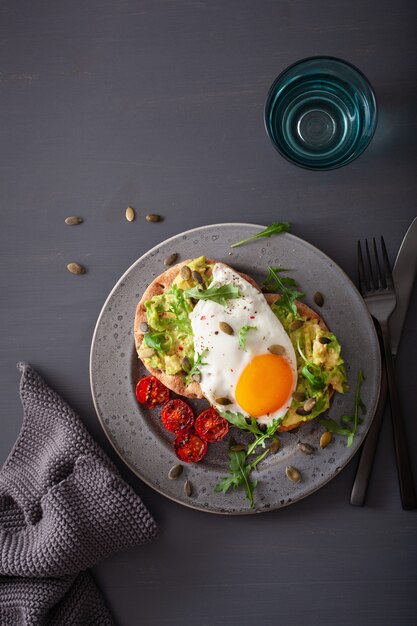 Breakfast avocado sandwich with fried egg and tomato