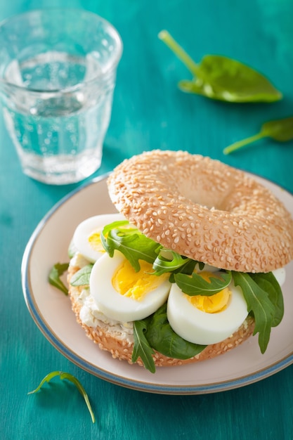 Foto colazione bagel con uovo, crema di formaggio e rucola