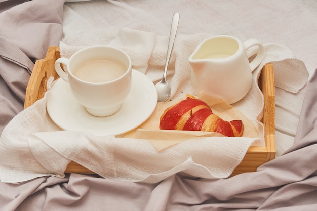 Breakfast in bed, coffee with cream, croissants in jam