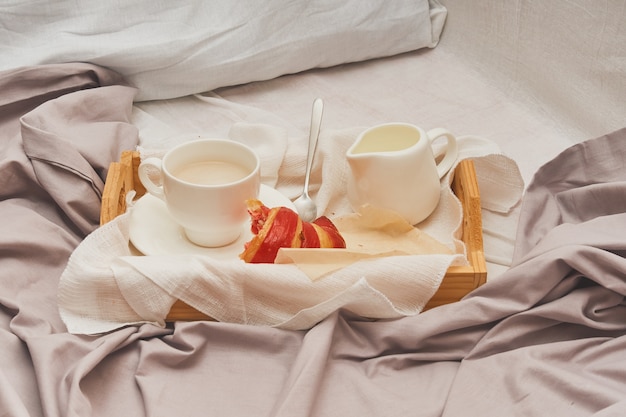 Breakfast in bed, coffee with cream, croissants in jam