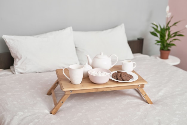 Breakfast in bed in hotel room. Accommodation. Breakfast in bed with tea cup with pancakes on tray on bed