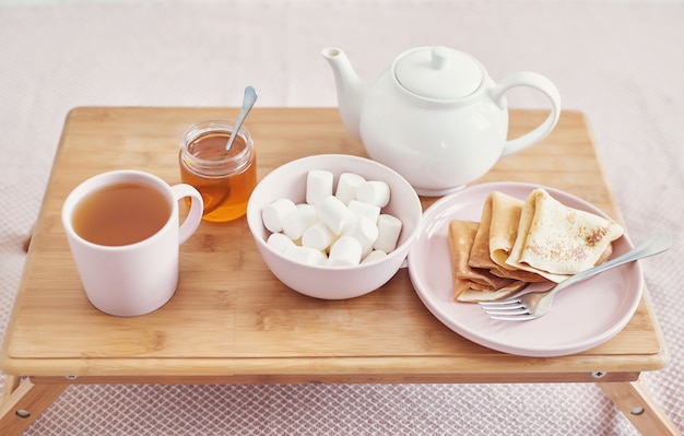 Breakfast in bed in hotel room. Accommodation. Breakfast in bed with tea cup with pancakes on tray on bed