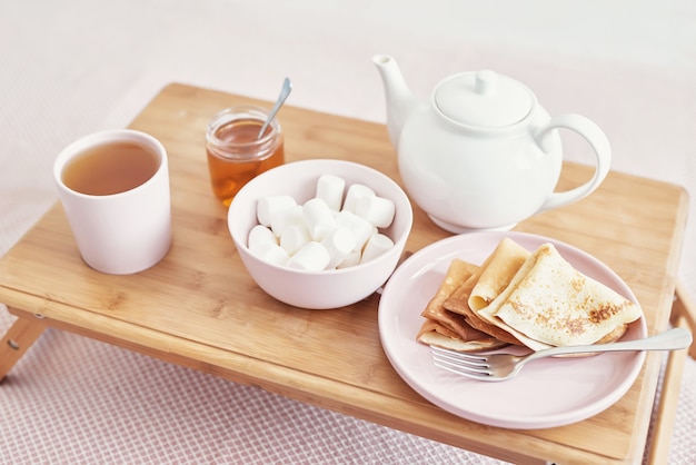 ホテルの部屋でベッドで朝食。宿泊施設。トレイにパンケーキとティーカップとベッドで朝食します。