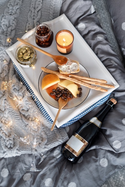 Breakfast in bed, a tray with cheese, grissini, jam from young fir cones and a candle