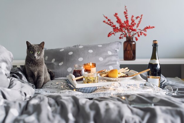 Breakfast in bed, a tray with cheese, grissini, jam from young fir cones, champagne and a candle