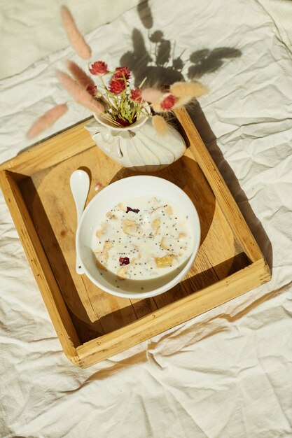 Breakfast in bed, try with bowl muesli, granola and flower in sunlight at home, chambermaid bringing tray with breakfast in hotel room, good service