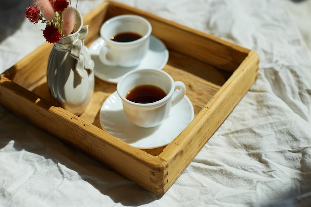 Завтрак в постели, попробуйте две чашки кофе и цветок при солнечном свете дома, горничная приносит поднос с завтраком в гостиничном номере, хорошее обслуживание