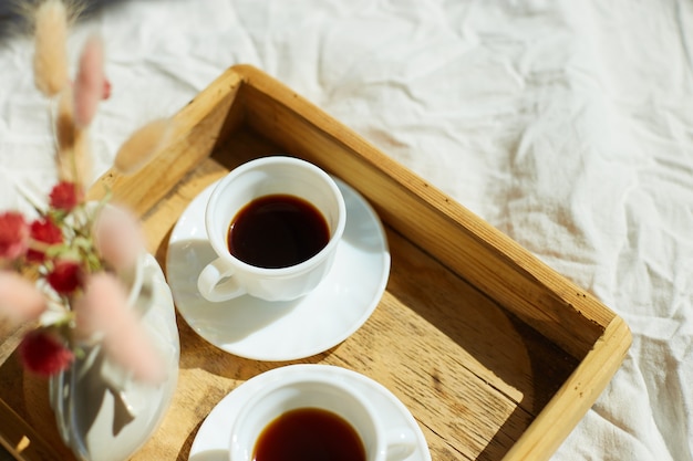 Breakfast in bed, try with two cups coffee and flower in sunlight at home, chambermaid bringing tray with breakfast in hotel room, good service