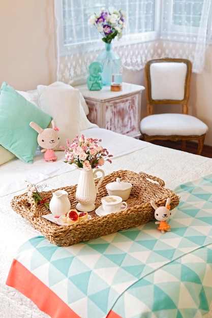 Breakfast in bed, wicker tray with a cup of coffee with milk, cookies and flowers