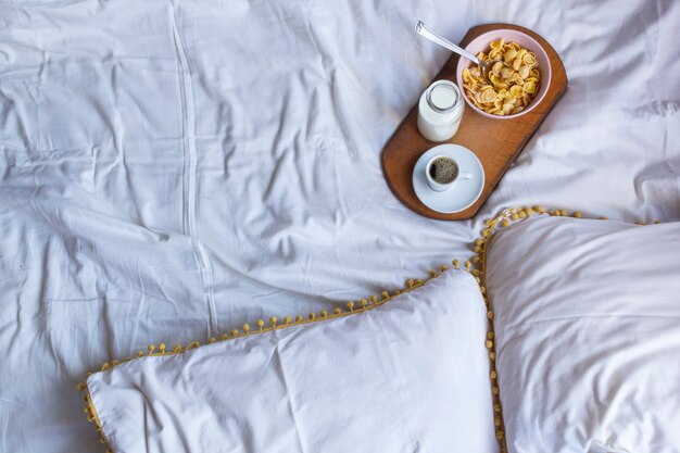 Breakfast in bed with corn flakes, milk and coffee