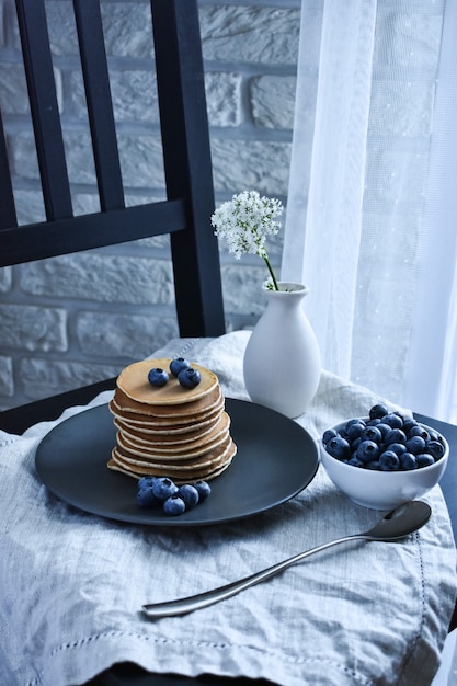 Photo breakfast on the bed with pancakes and fresh blueberries