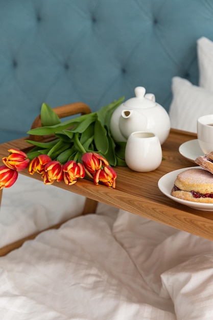 Breakfast in bed on a wooden table tray morning light
flowers