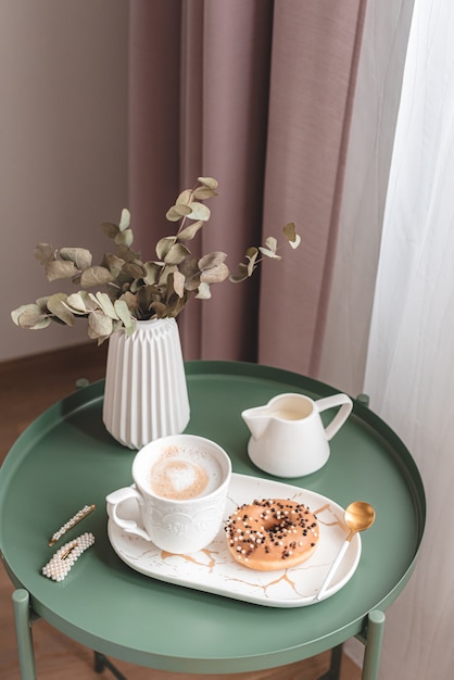 Photo breakfast in bedroom with cup with cappuccino and doughnut