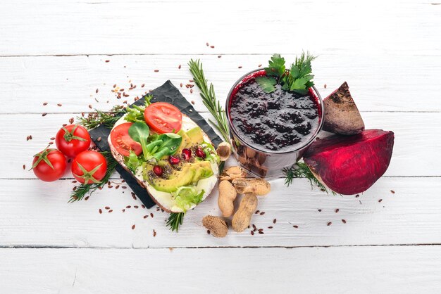 Breakfast Beetroot juice and avocado burger and vegetables On a wooden background Top view Copy space