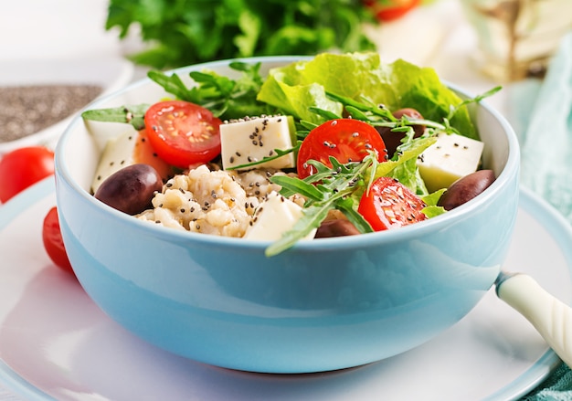 Фото Чаша для завтрака с овсянкой, помидорами, сыром, листьями салата и оливками. здоровая пища. вегетарианская чаша будды