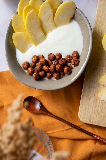 Breakfast bowl of yogurt with apple and hazelnuts