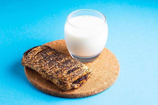 Breakfast bread and a cup of milk on yellow and blue background