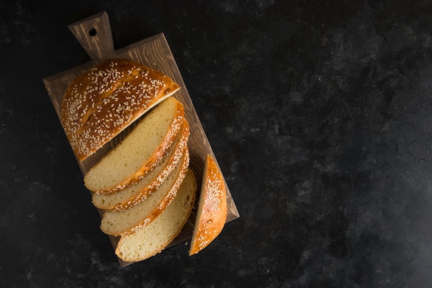 Photo breakfast bread on cutting board dark background