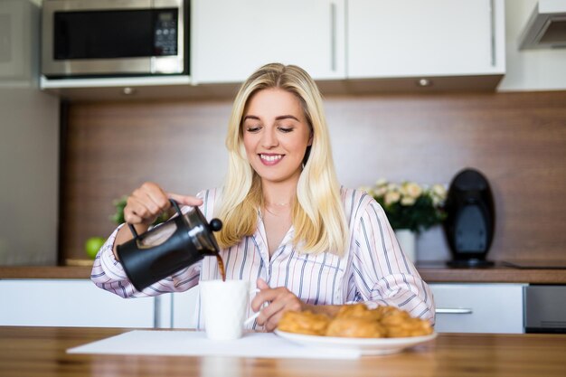 Foto concetto di colazione bella donna che versa il caffè nella cucina moderna