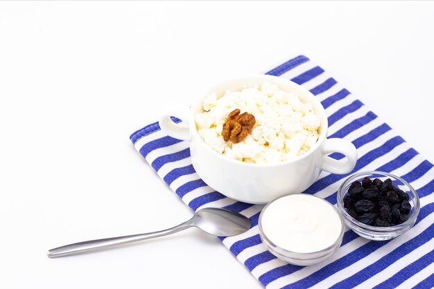 Photo breakfast concept. cottage cheese with walnuts, raisins and sour cream on a light surface and a towel. white