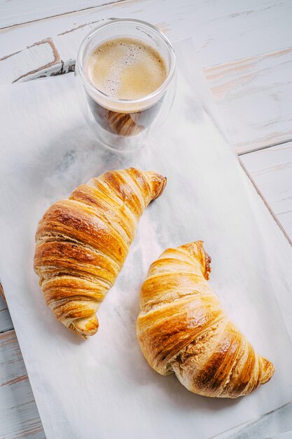 朝食のコンセプトホットで新鮮なクロワッサンと一杯のコーヒー