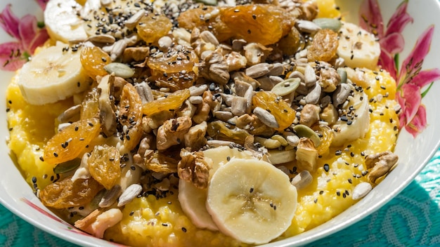 Breakfast corn porridge with nuts, raisins, slices of banana, sesame.