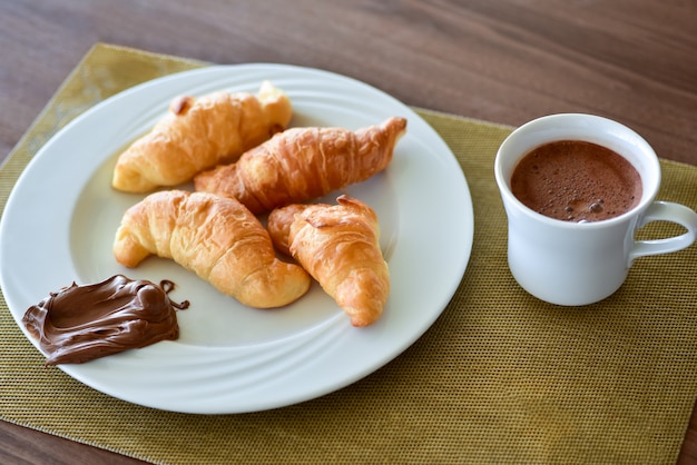 Breakfast croissant with chocolate cream on a plate.