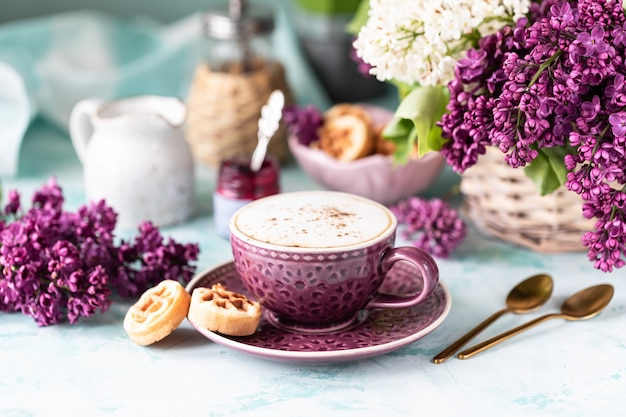 朝食一杯のコーヒー、ワッフル、牛乳、クリーム、ライラックの花。朝