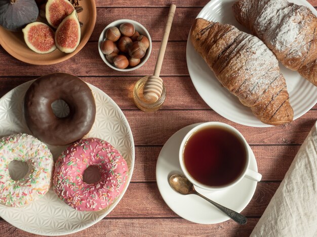 Breakfast donut croissant figs nuts on the plates on the table