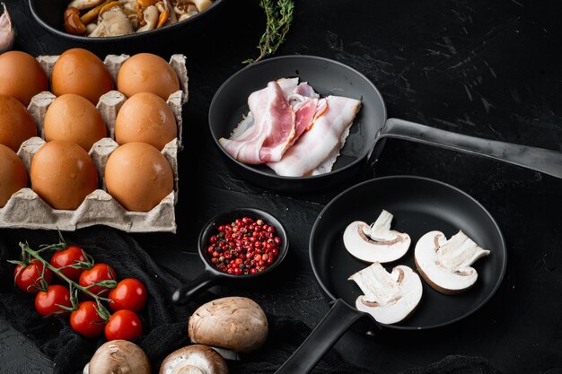 Photo breakfast egg ingredients mix in cast iron frying pan, on black background