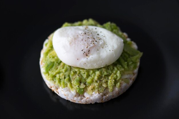 Breakfast Egg Poached and Avocado Sandwich on a plate with a dark black background