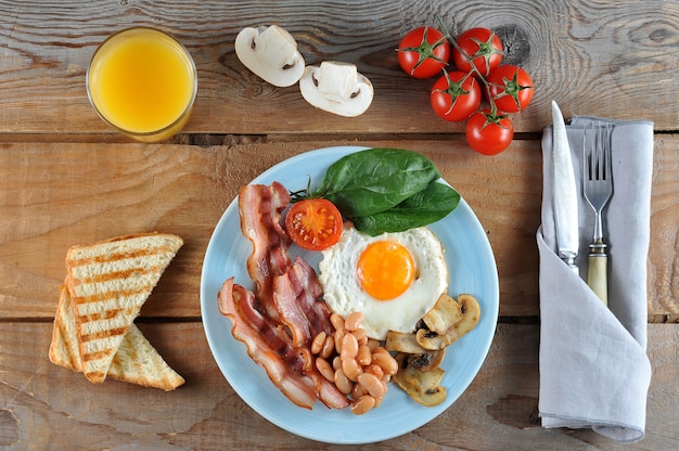 Colazione a base di uova con pancetta, fagioli, funghi, pomodori e spinaci