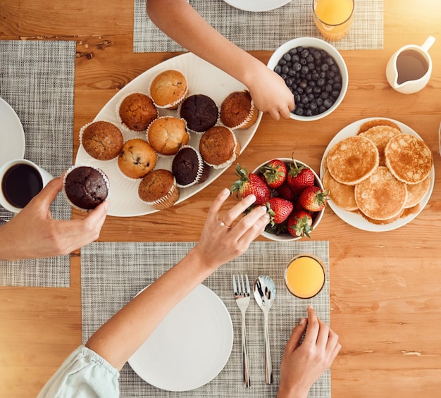 朝食用の食べ物とダイニングルームでお腹を空かせた人々が、朝は健康的でテーブルセッティングや家の上で食事をしています。フルーツパンケーキと、栄養やダイエットのためのイチゴやマフィンプレートの上に手を置きます