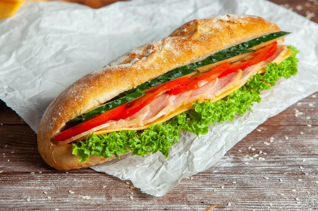 Prima colazione di croissant fresco con formaggio di prosciutto e foglia di insalata su fondo di legno bianco