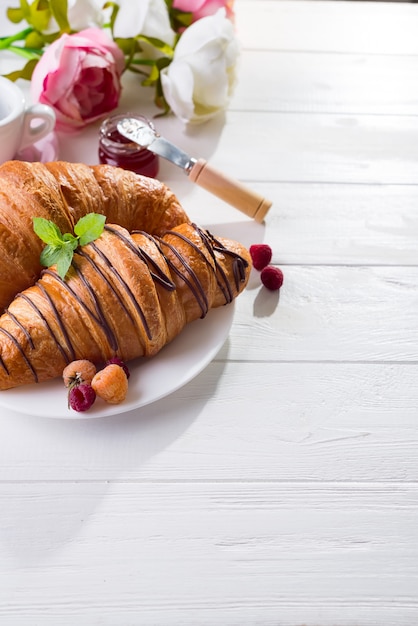 Breakfast freshly baked croissant decorated with jam and chocolate