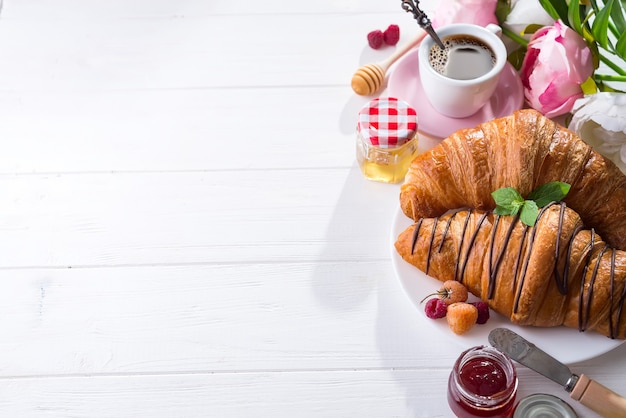 Breakfast freshly baked croissant decorated with jam and chocolate