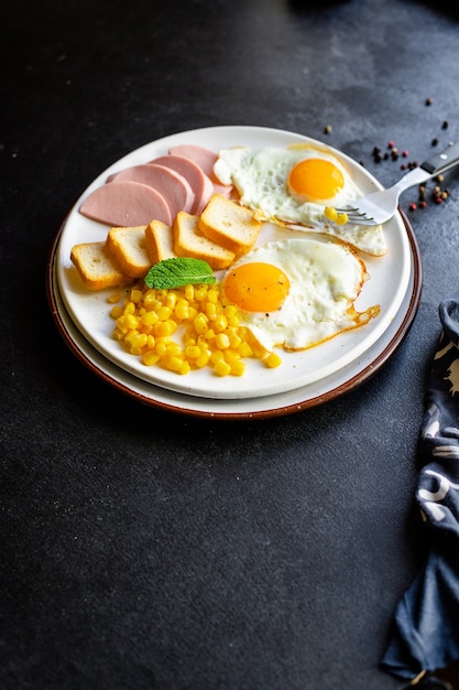Завтрак, жареные яйца, хлеб, тосты, овощи, кукуруза, сыр и многое другое на столе, где подают полезные закуски