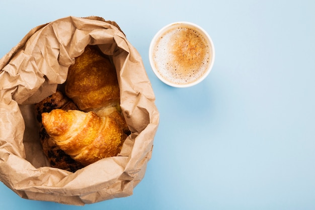 Breakfast to go - croissants and coffee with milk on blue background. Top view, copy space