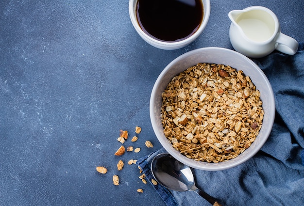 朝食グラノーラ、牛乳やヨーグルト、石のテーブル背景に木製トレイ上の蜂蜜。上面図