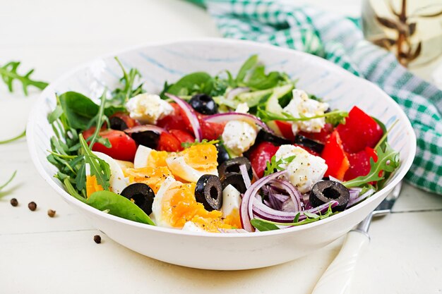 Breakfast Greek salad and boiled eggs Fresh vegetable salad with tomato cucumbers olives arugula and cream cheese Trendy food